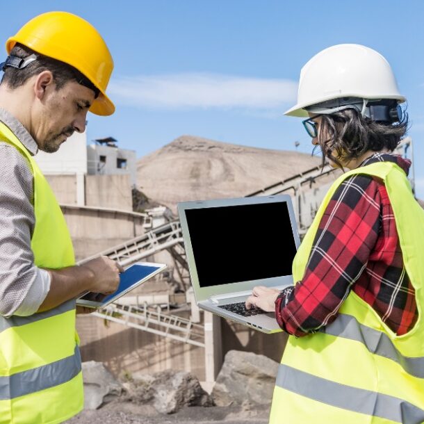 Two construction workers using a timesheet app on their mobile and tablet on the site